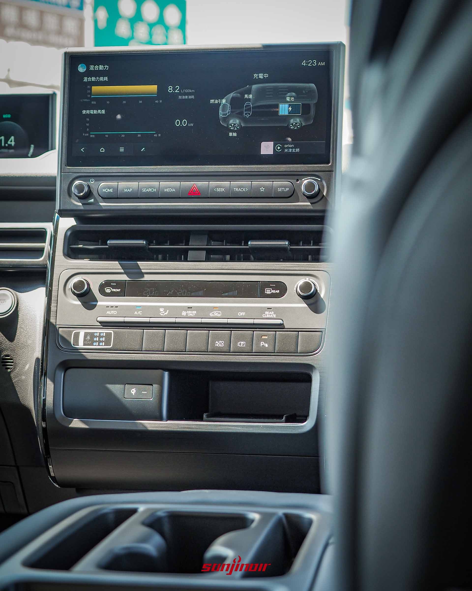 特寫 Hyundai Staria 的 12.3 吋中控螢幕,畫面上正顯示著油電混合動力系統的即時能量流向圖,下方為空調與快捷實體按鍵。