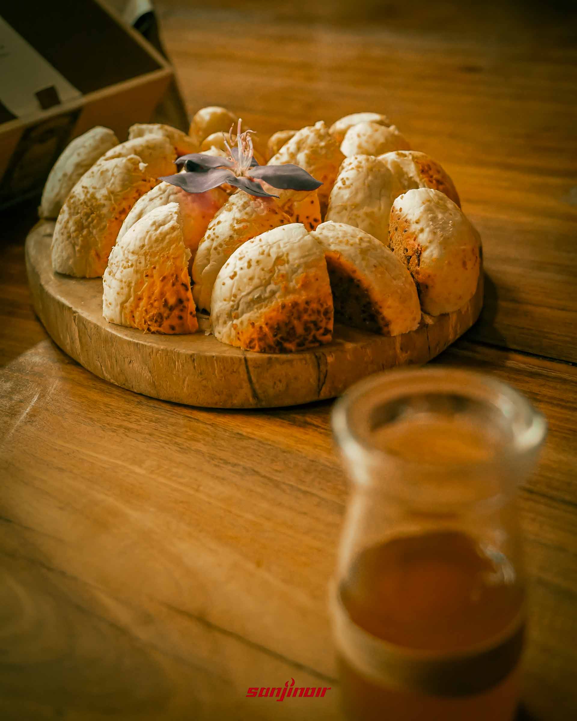 木板上切開的酒麴麵包前方有模糊玻璃瓶。