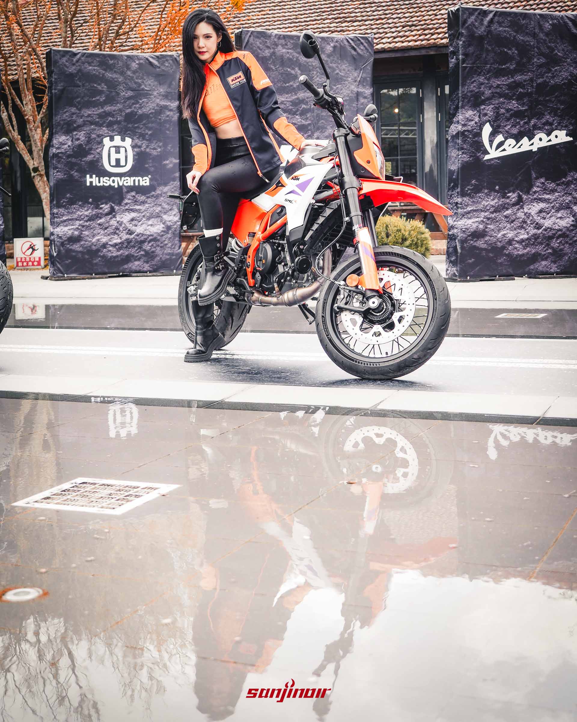 模特兒DuDu坐在KTM 390 SMC R摩托車上，地面積水清晰反射出人與車的倒影。