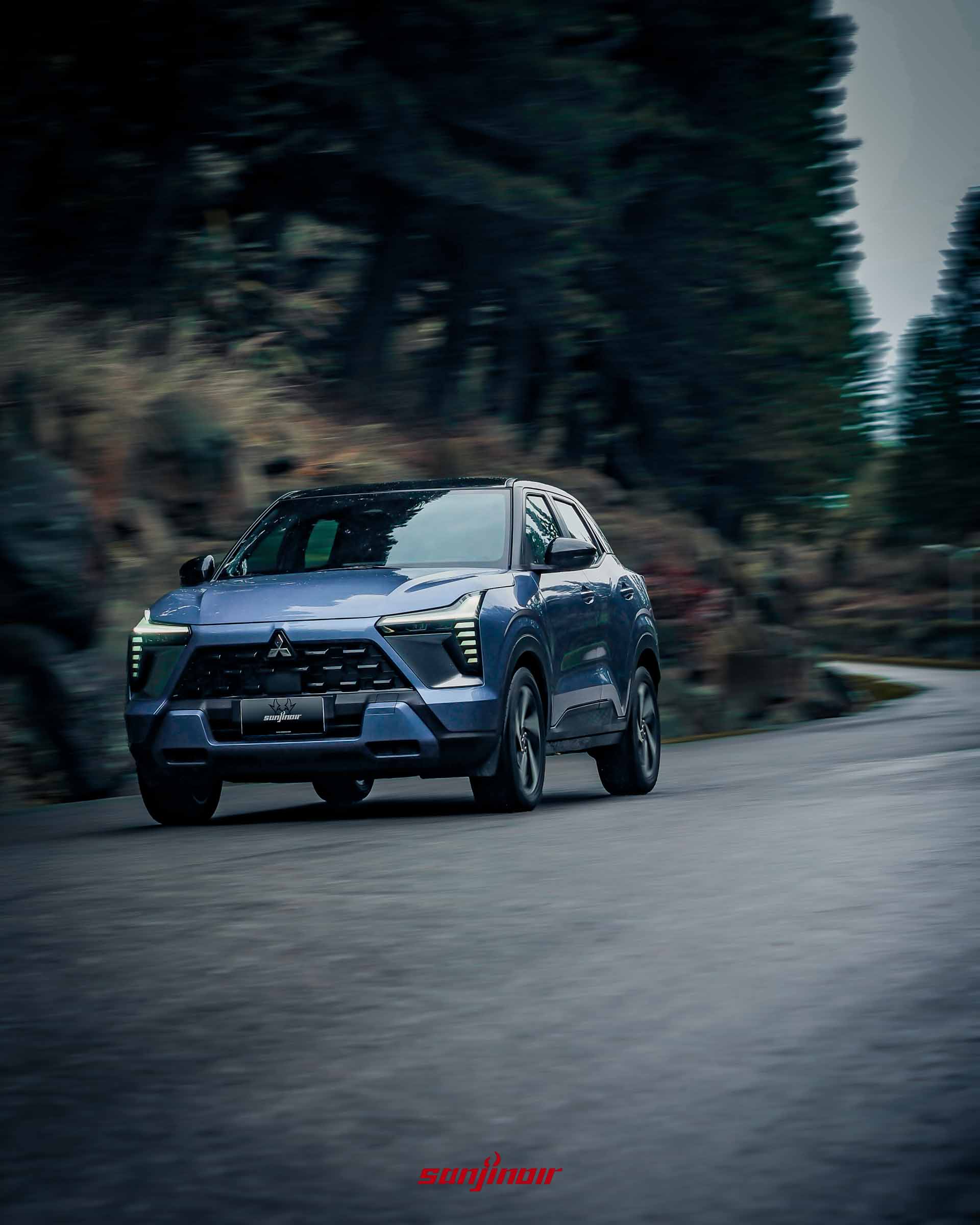 藍色Mitsubishi XForce狂享版在柏油山路上動態行駛的車頭視角。