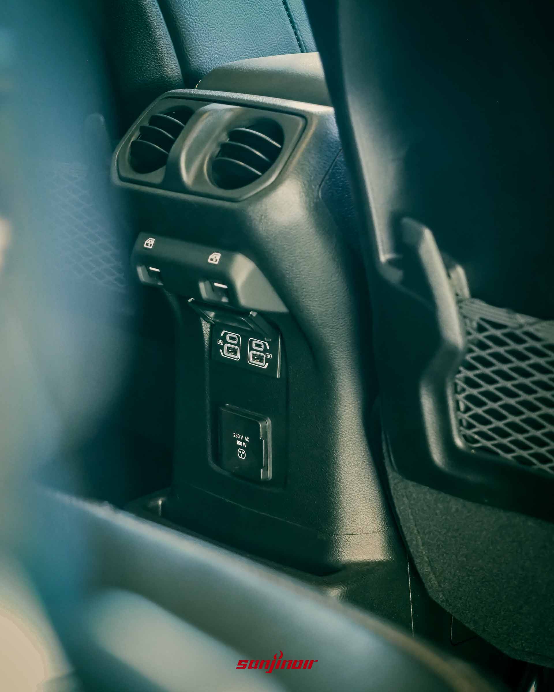 Jeep Wrangler Sahara 後座中央扶手後方的配置,包含冷氣出風口、電動車窗開關、USB 接口及 230V 150W 電源插座。