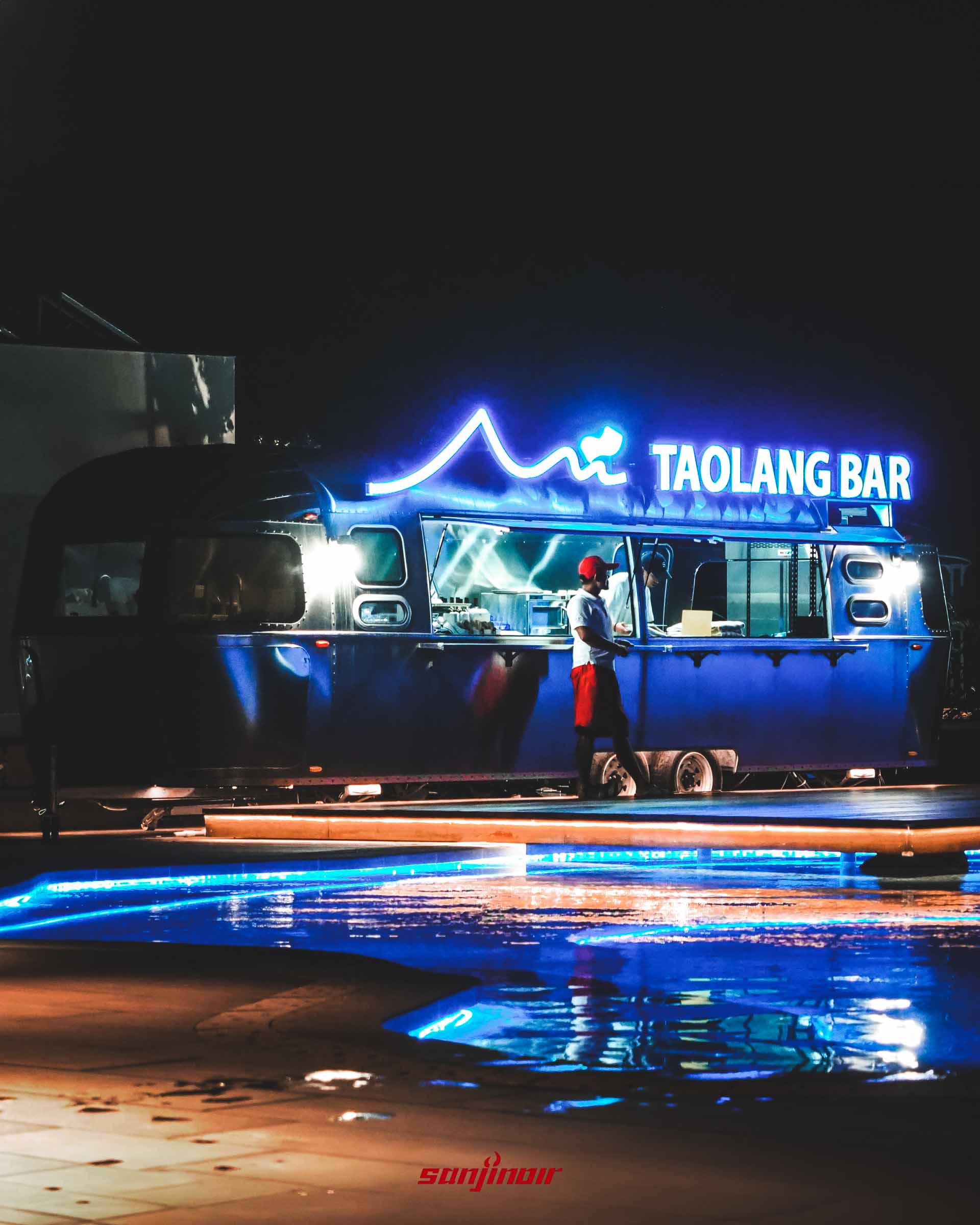 泳池畔的銀色Airstream復古餐車,車頂亮著藍色霓虹燈字樣TAOLANG BAR,裡面有工作人員。