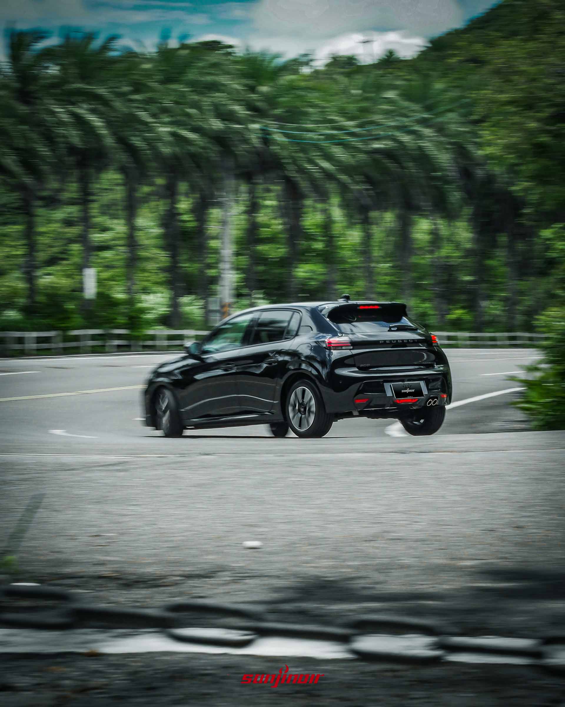黑色PEUGEOT 208 Hybrid行駛於山路的車尾動態追焦照。