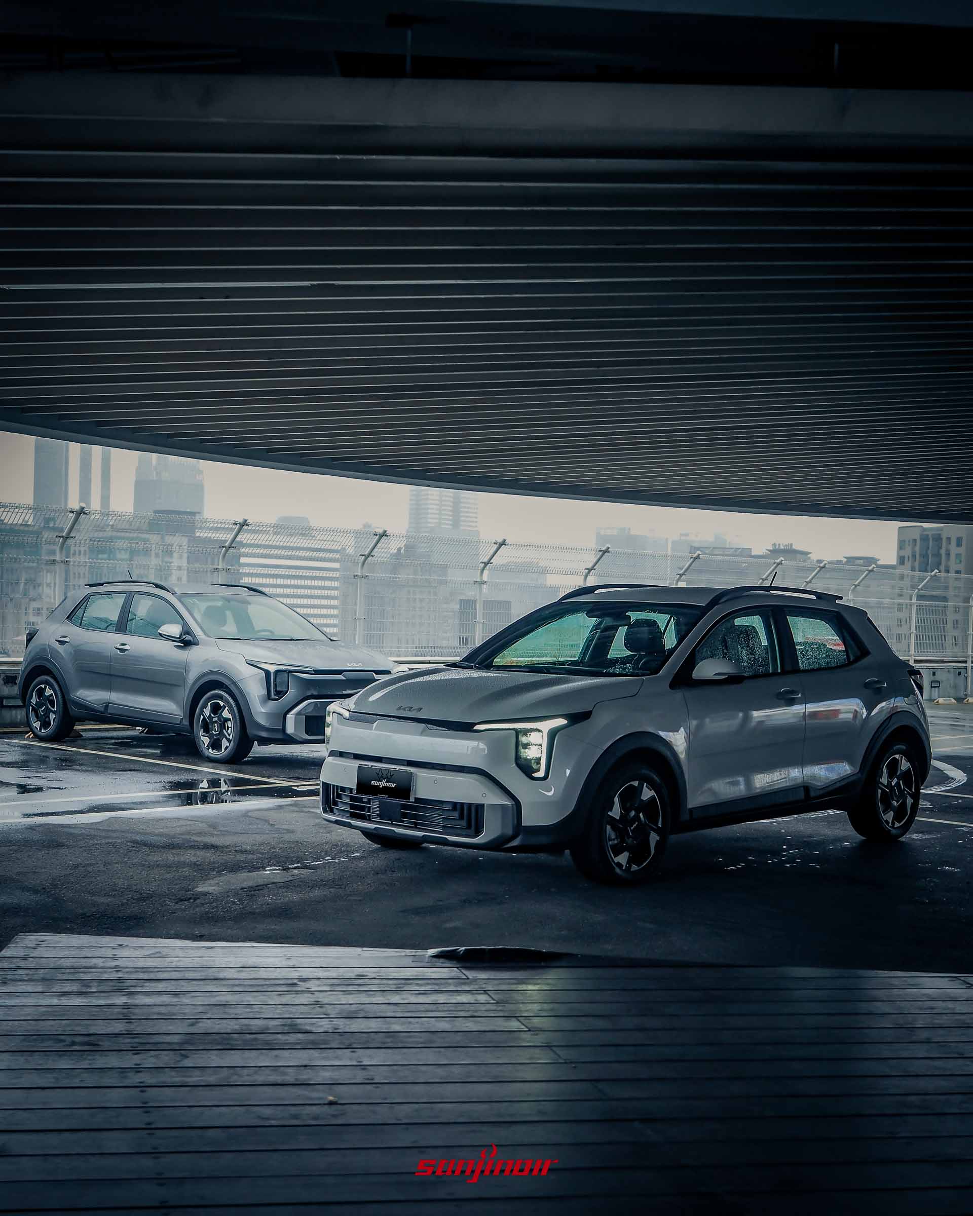兩輛白色 2026 Kia Stonic 停放於頂樓停車場,背景為陰雨天的城市高樓與橋樑,展示 Digital Tiger Face 前臉與 Star Map 燈組。