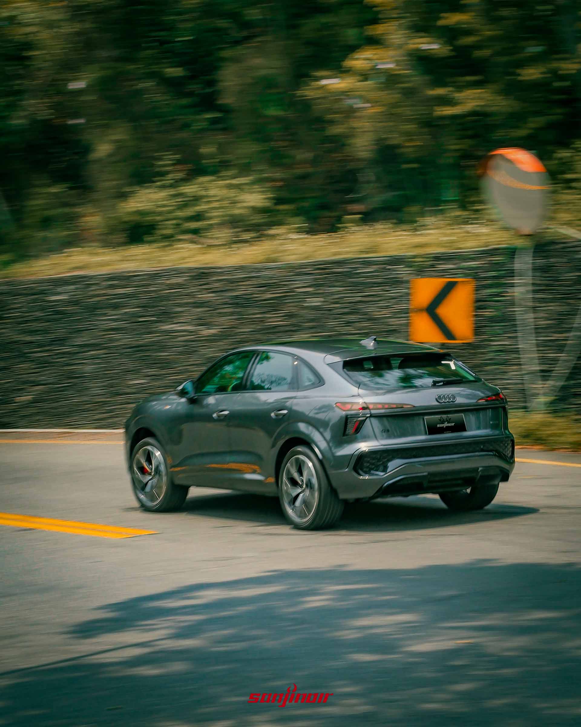 Audi Q3在山路過彎時的車尾動態追焦照片，背景帶有速度感模糊。