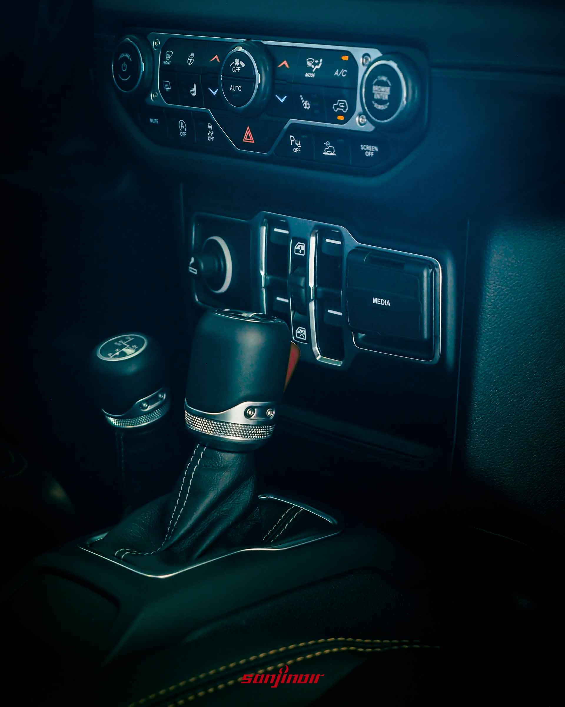 Jeep Wrangler Sahara 的中控台下半部與中央鞍座特寫,包含排檔桿、加力箱排檔桿、車窗控制開關與媒體接口。