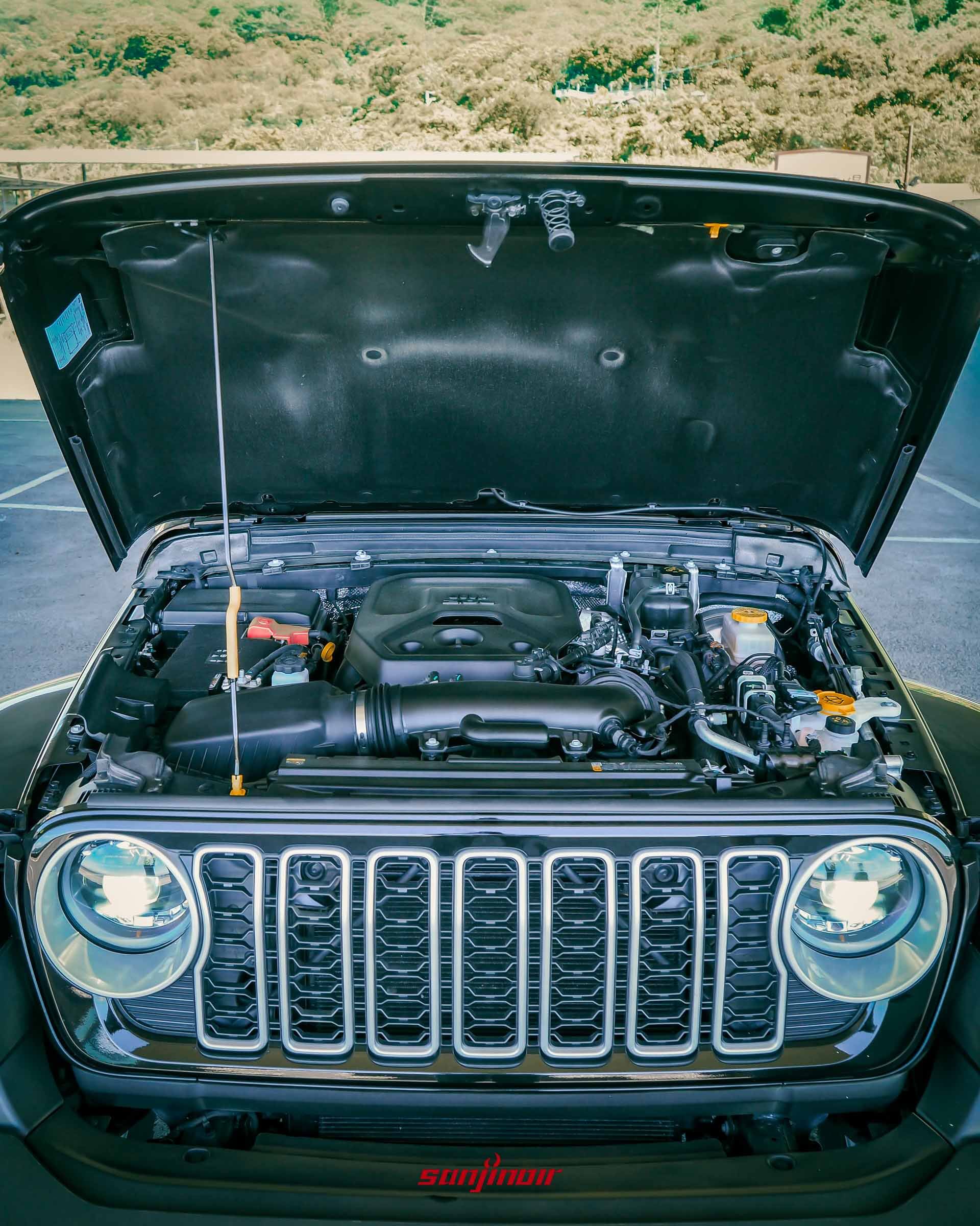 引擎蓋掀起的 Jeep Wrangler Sahara,展示引擎室內的 2.0L 渦輪增壓引擎配置,車頭的水箱護罩與圓燈清晰可見。