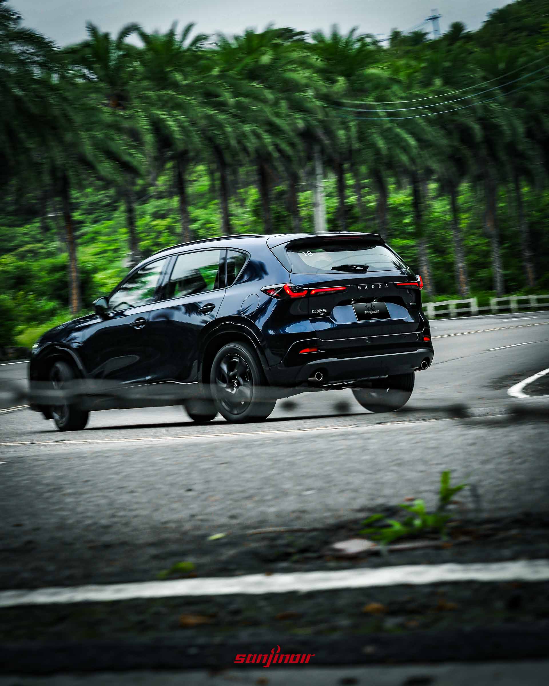 深藍色MAZDA CX-5在山區彎道中駛離的車尾側後方動態追焦照。
