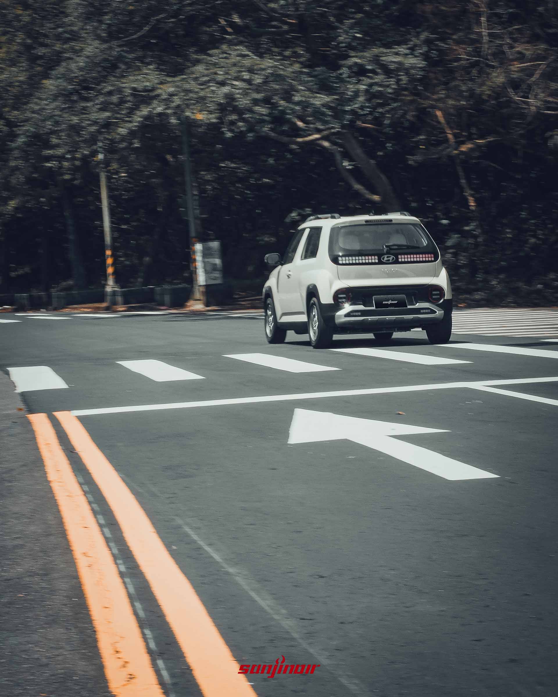 Hyundai Inster 行駛於路口的後側45度畫面。