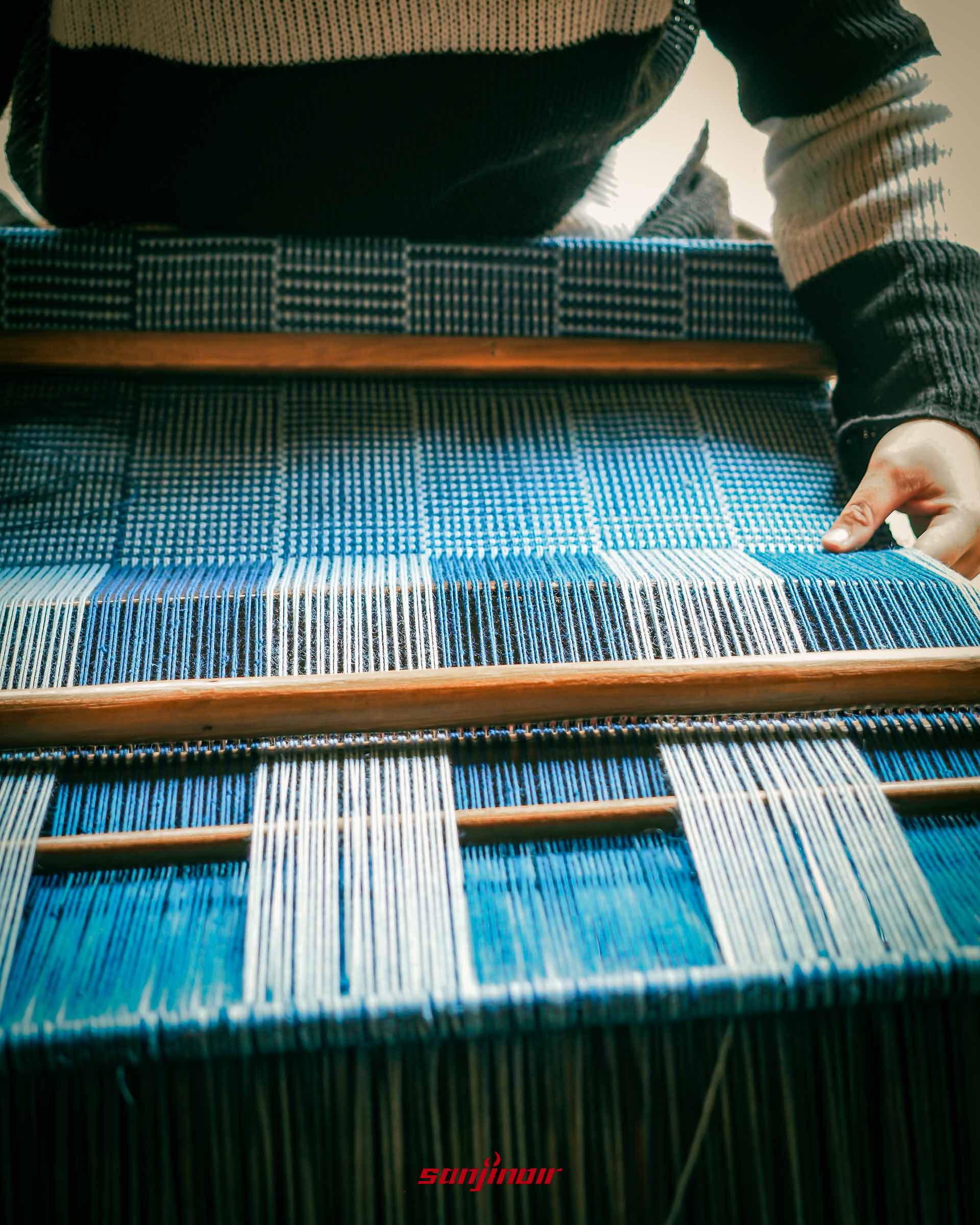 織布機上正在編織藍白相間幾何圖案布料特寫。