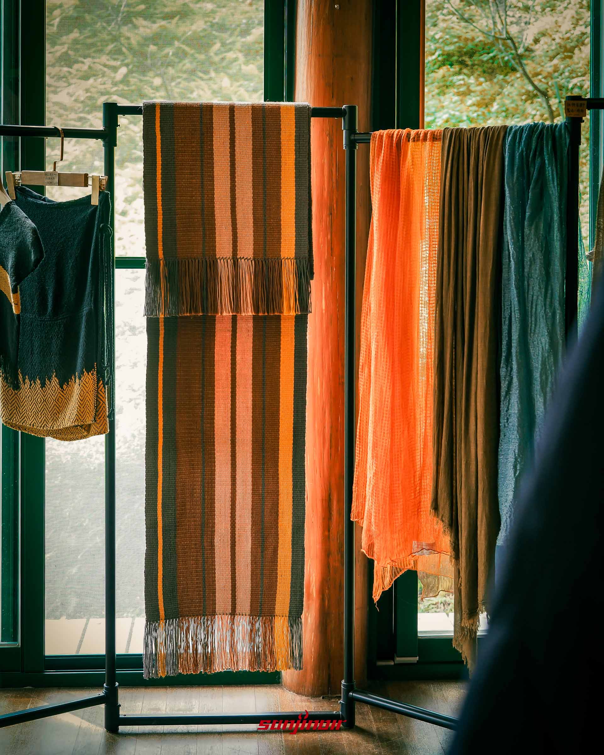 掛在黑色衣架上多款彩色泰雅族手工編織布料。