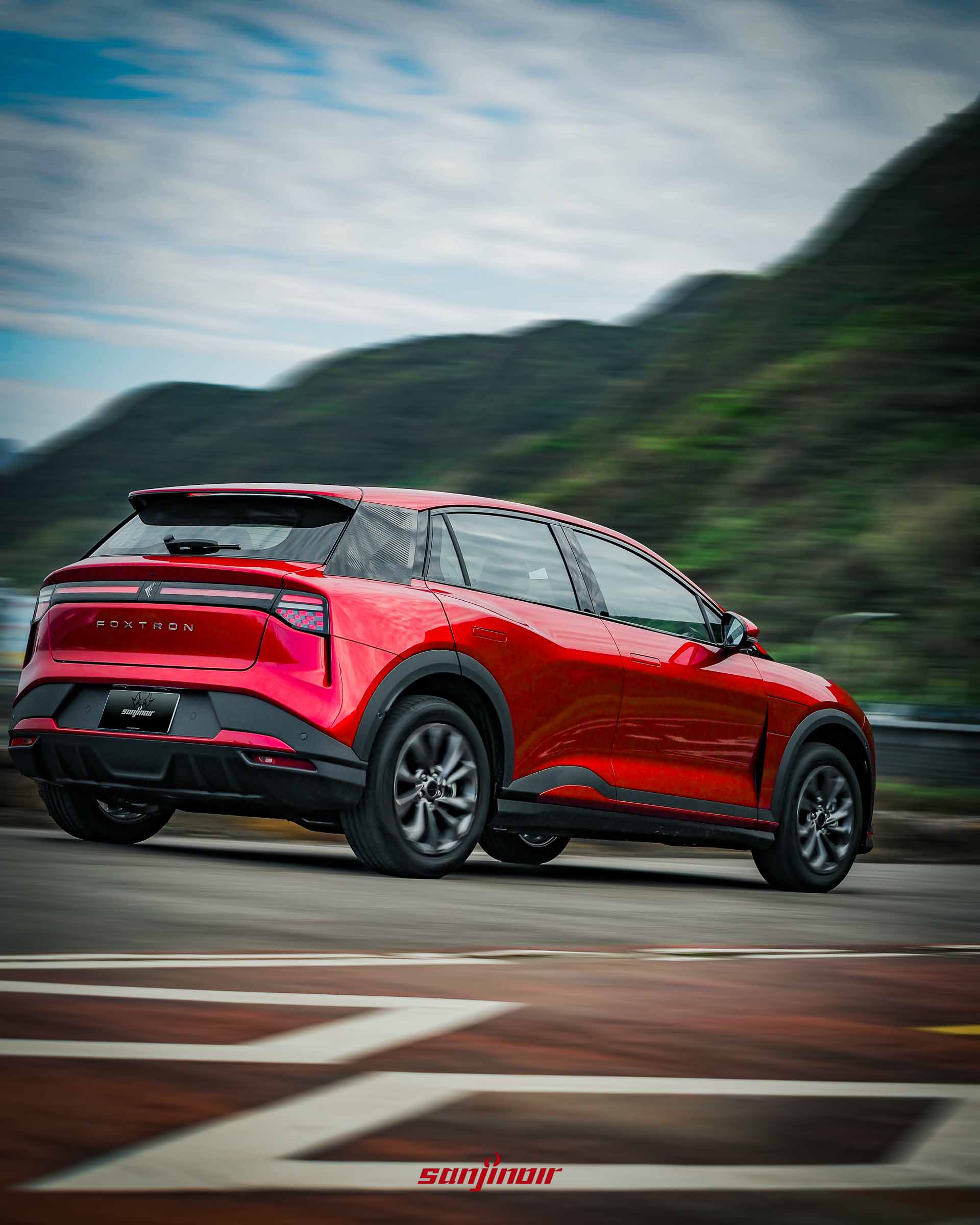 紅色Foxtron Bria Emerge在海岸公路上行駛的右後側動態追焦照片。