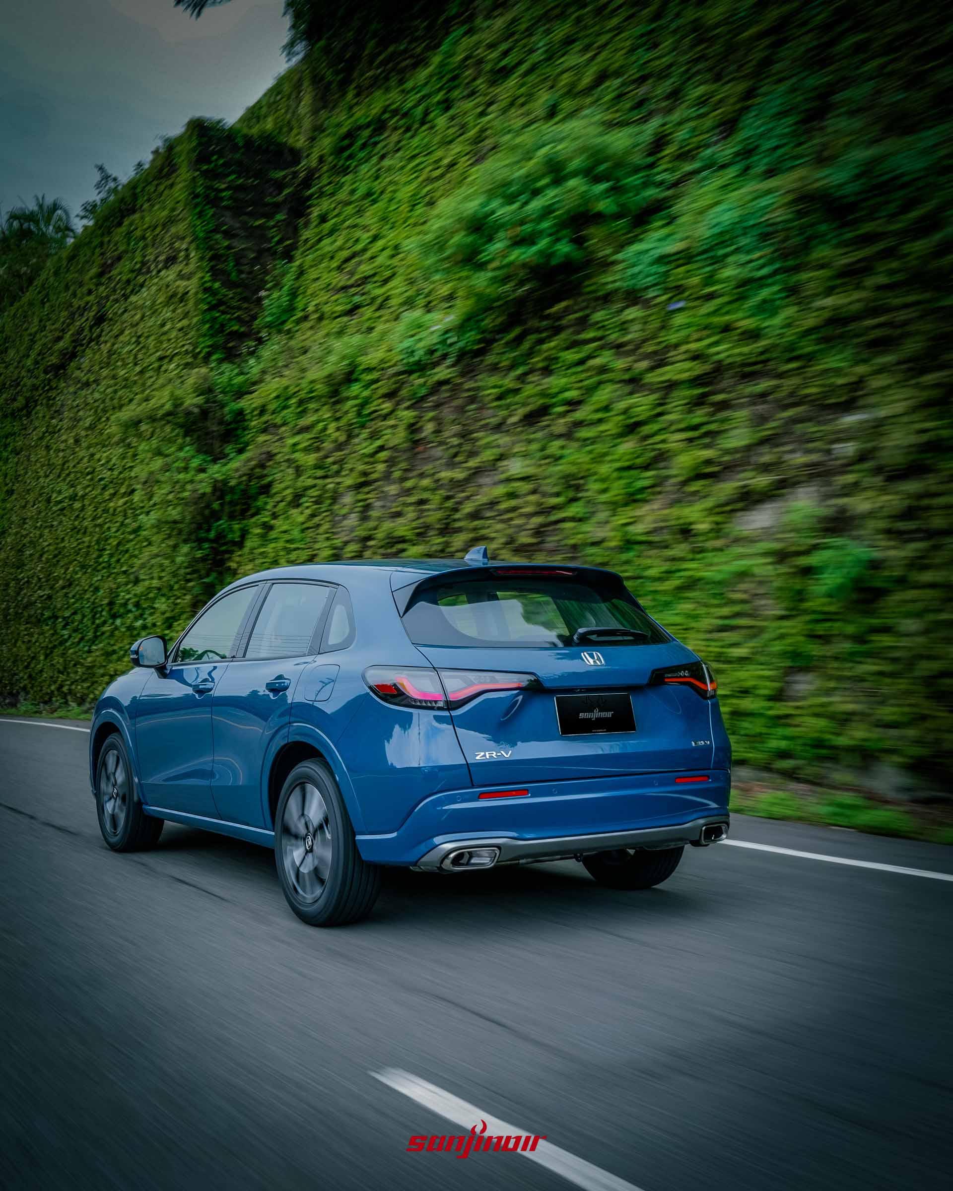 2026 HONDA ZR-V e:HEV在綠意山路中動態過彎的車尾側視角。