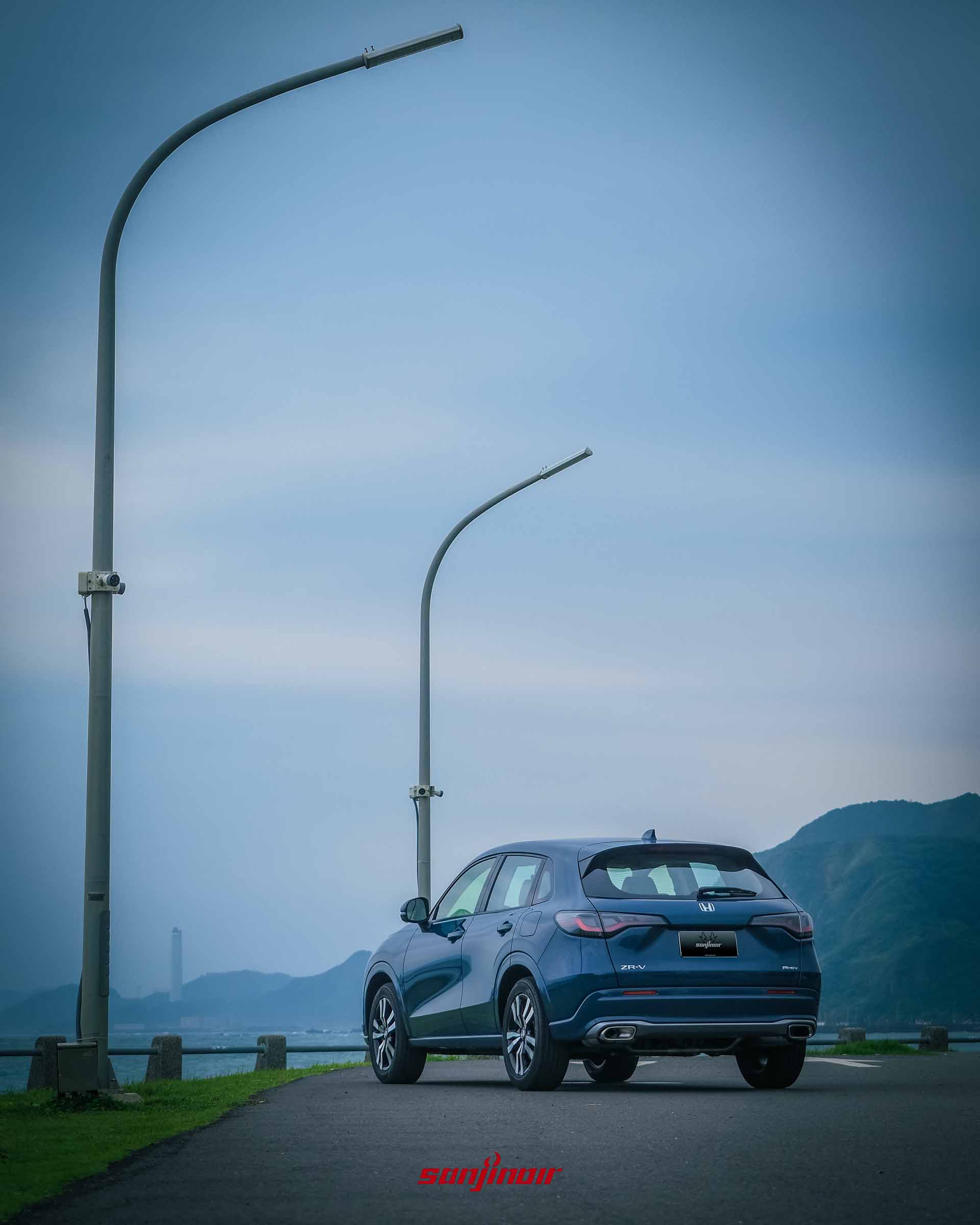 2026 HONDA ZR-V e:HEV停放於海岸道路旁，與路燈和海景相伴的靜態車尾視角。