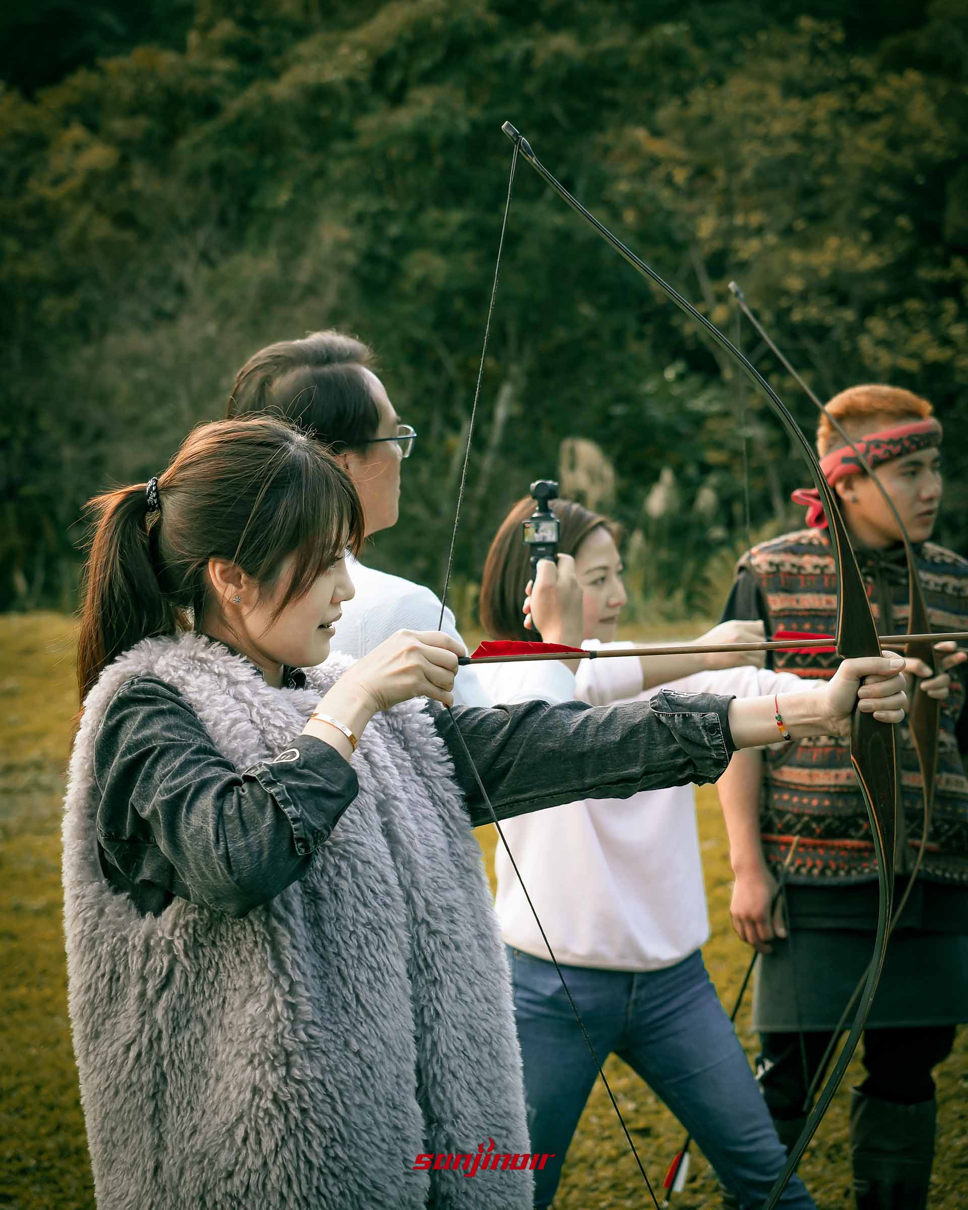 《一名空姐的流水帳日記》作者Zoe王小凡正在體驗傳統射箭後方有其他人觀看與拍攝。