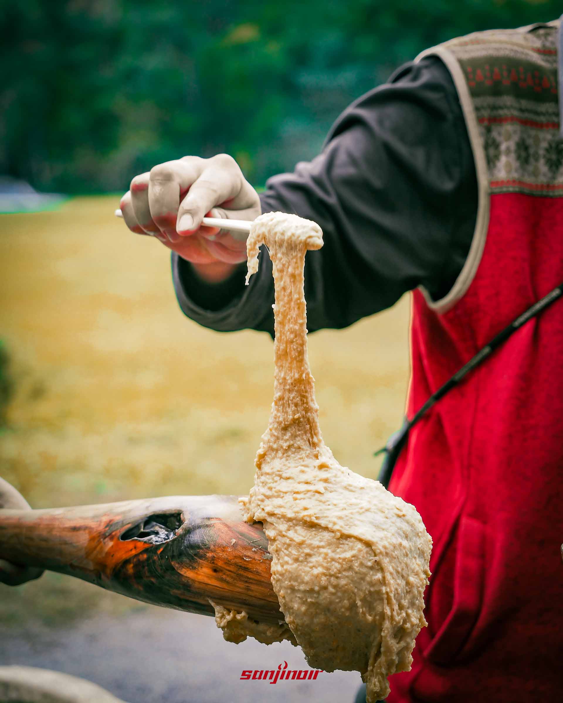 木杵上黏著搗好麻糬有人正用筷子將其夾起。